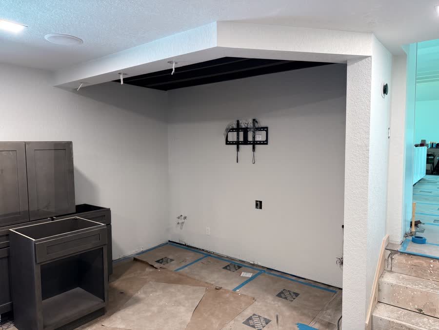 Empty alcove with a TV mount and the first bar cabinets waiting to be set