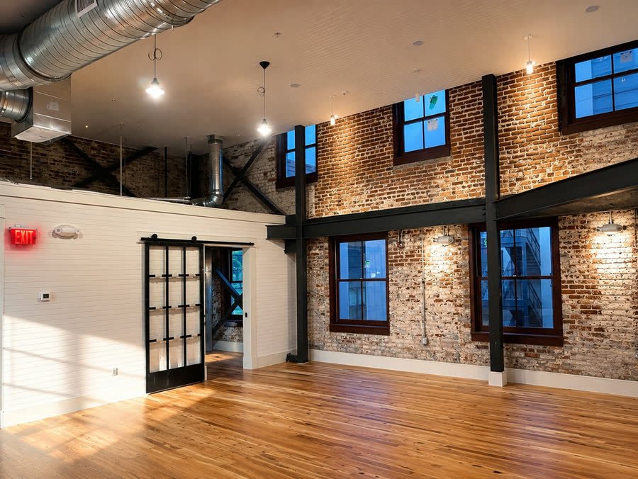 Exposed brick wall with steel beams, wall sconces and a sliding steel and glass door