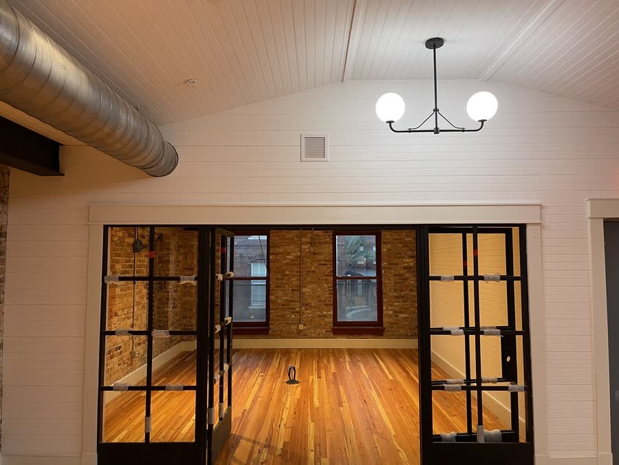 Steel-framed glass doors opening into a brick-walled room