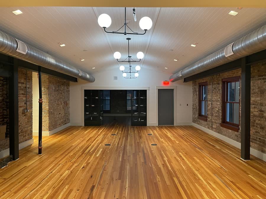 Renovated brick loft with new wood floors, globe chandeliers and black steel columns