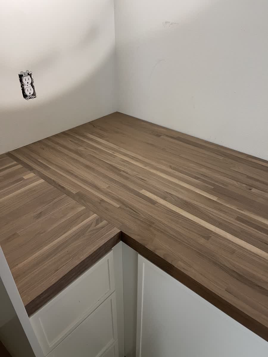 L-shaped butcher block counter on white built-in cabinets