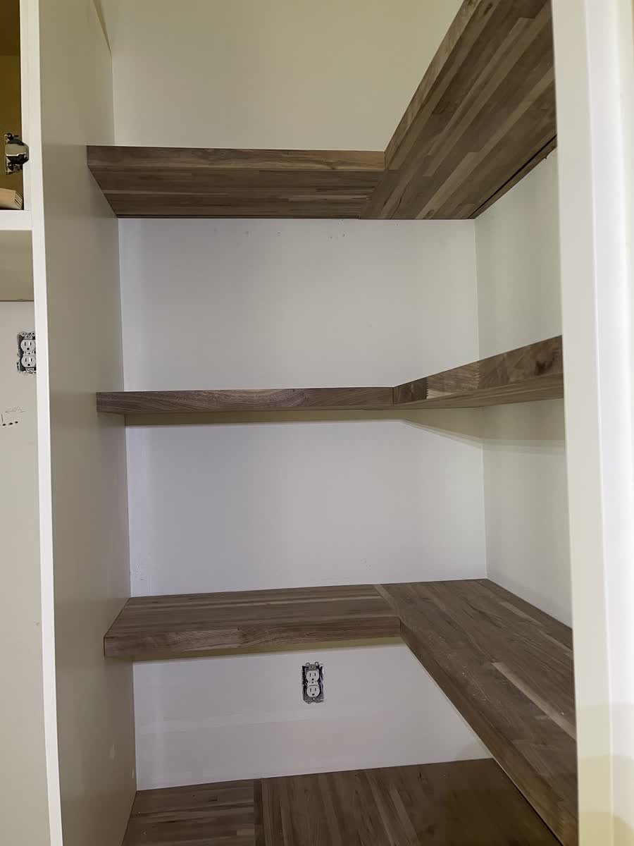 Built-in pantry with wrap-around butcher block shelves on white walls