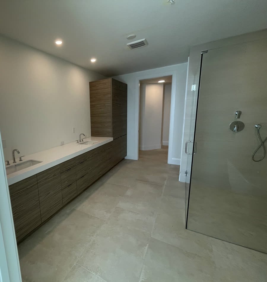 Floating wood vanity next to a frameless glass shower