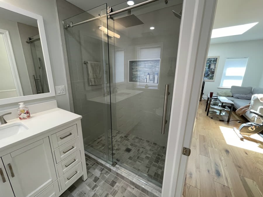 Bathroom remodel with a frameless sliding glass shower door and white vanity