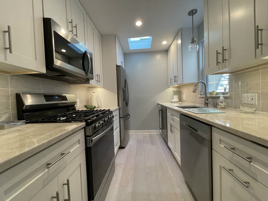 Galley kitchen remodel with white shaker cabinets and stainless appliances