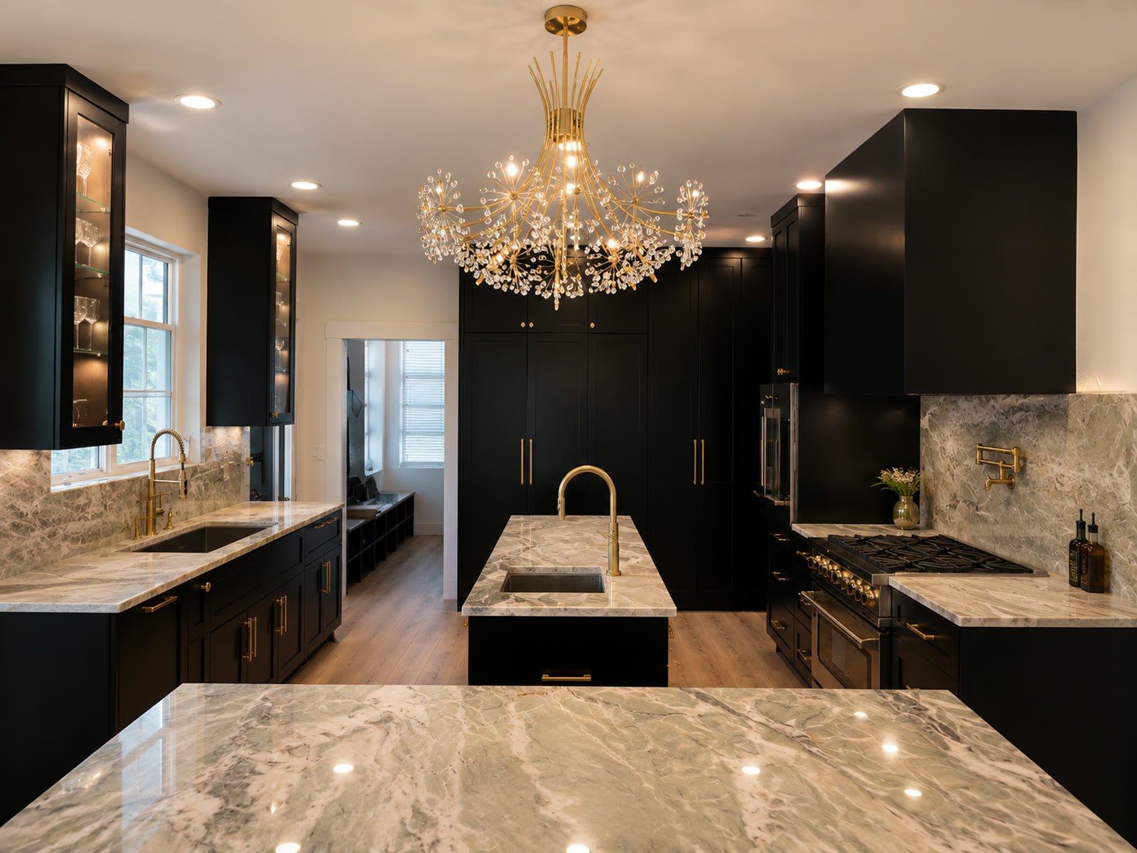 The finished black and gold kitchen with marble counters, a brass faucet and a crystal chandelier