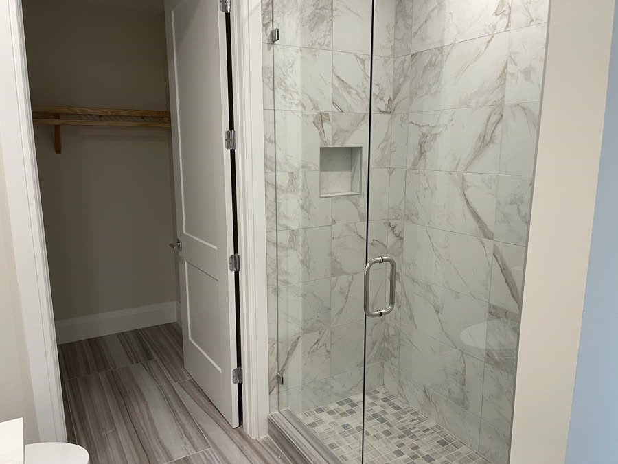 Marble look shower with a recessed niche and glass door