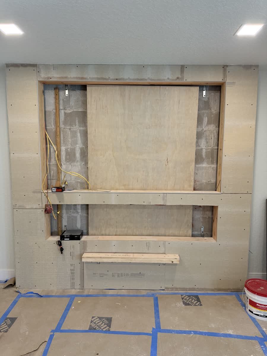 Media wall framed and covered in cement board with openings for the TV and fireplace