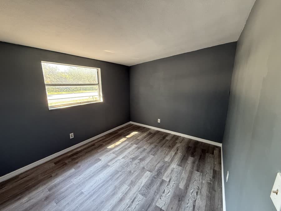 Rebuilt bedroom with charcoal walls, white baseboards and new vinyl plank flooring