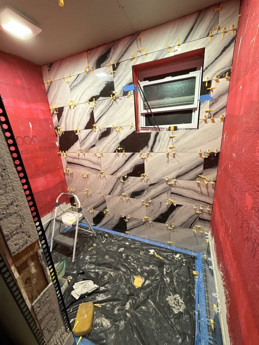 Large graphic wall tiles being set with leveling clips around the window
