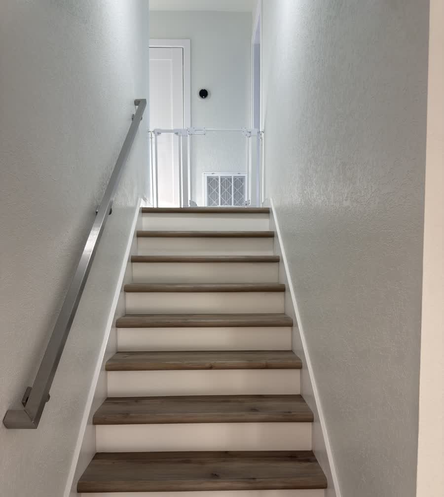 Renovated staircase with new wood treads, white risers and a brushed metal handrail