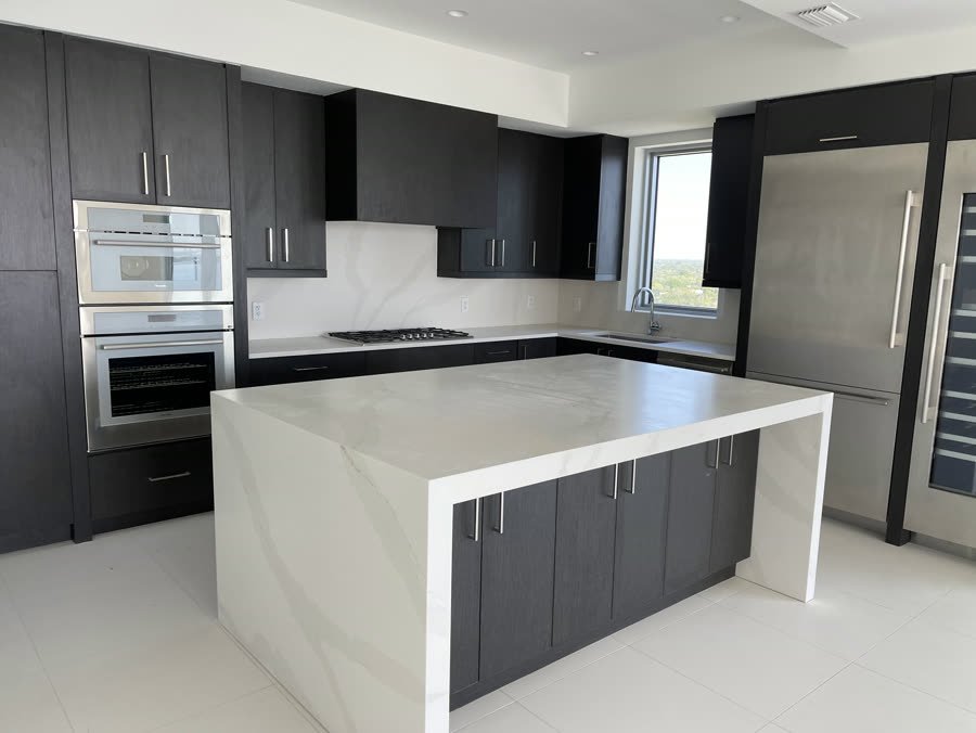 Two tone kitchen with dark cabinets and a white waterfall island