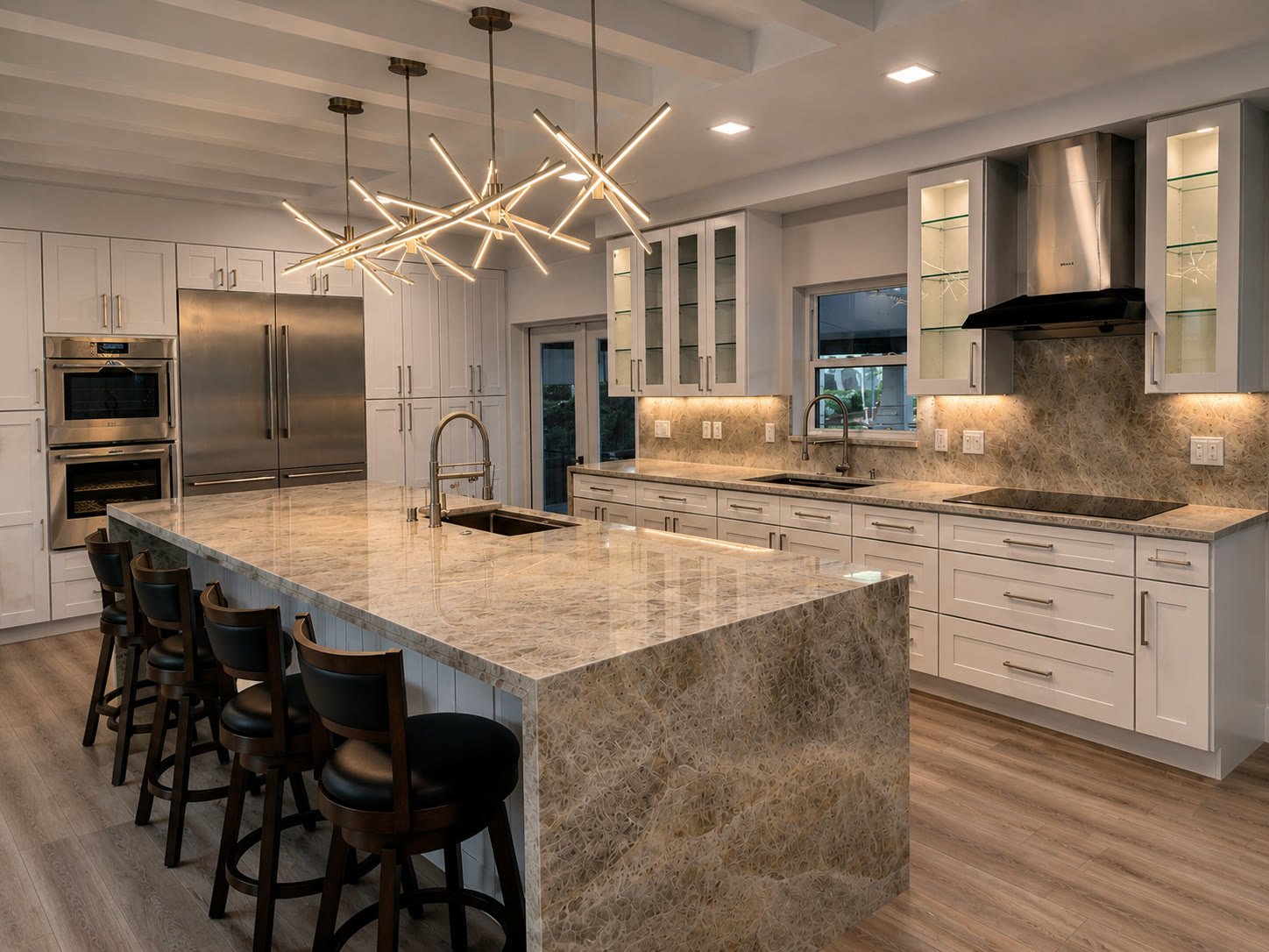 Remodeled Tampa kitchen with a quartzite waterfall island and brass starburst pendant lights